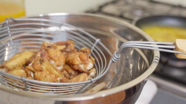 Chef tossing fried chicken wings in buffalo sauce