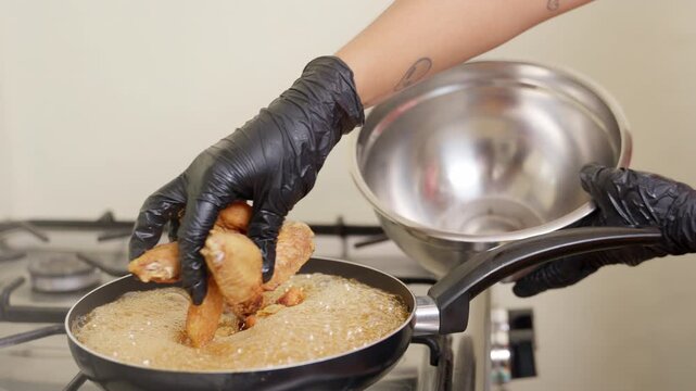 Chef deep frying chicken wings in oil