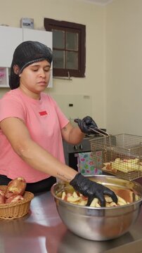Young woman frying french fries in a commercial kitchen deep fryer