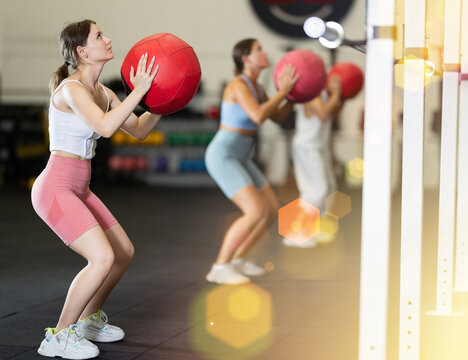Young athletic woman in sportswear training with ball in gym