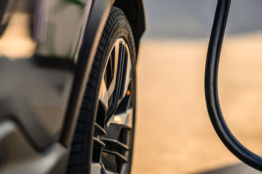 Close up of modern electric car wheel during charging session highlighting sustainable transport technology.
