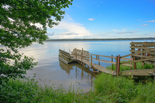 Quiet wooden dock beside calm Swedish lake at dusk.
