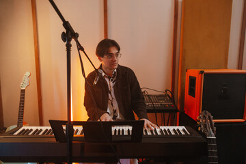 Young musician playing keyboard in a creative music studio © Drobot Dean