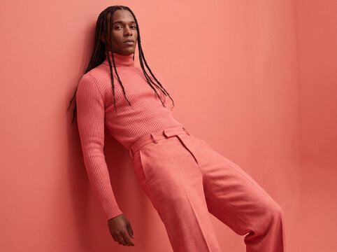 Stylish black man posing in pink turtleneck sweater
