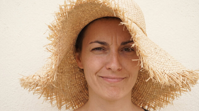 Woman wearing frayed straw hat looking at camera
