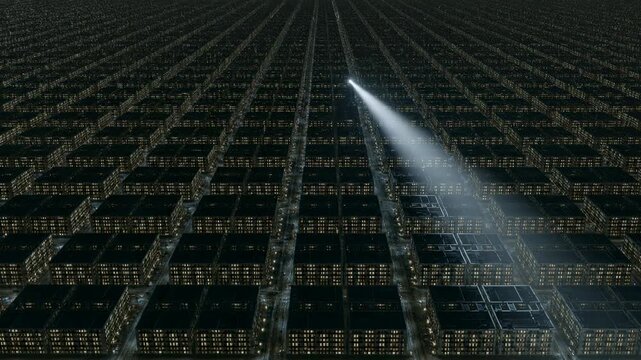 Searchlight shining on a vast grid of city buildings at night. Overhead aerial view of an infinite urban landscape with glowing windows. Futuristic city concept.
