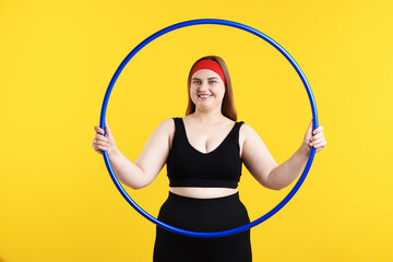 Overweight woman with hula hoop on yellow background © New Africa