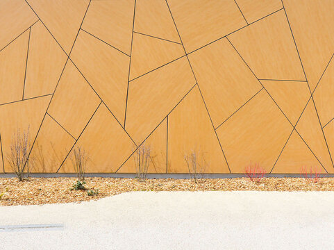 Modern geometric architectural facade with decorative panel cladding and minimalist landscaping