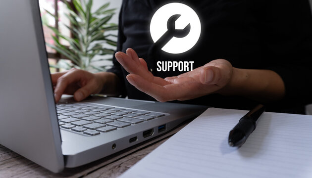 Person holds glowing support icon near laptop. Hands show ready assistance. Tech support or troubleshooting theme. Ideal for websites, manuals, or help guides