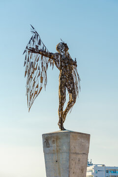 Ayia Napa, Cyprus - September 17 2021: Metal wire sculpture of Icarus rises on a pedestal on the coastal pedestrian promenade against a clear blue sky, outdoor art installation, urban landmark.