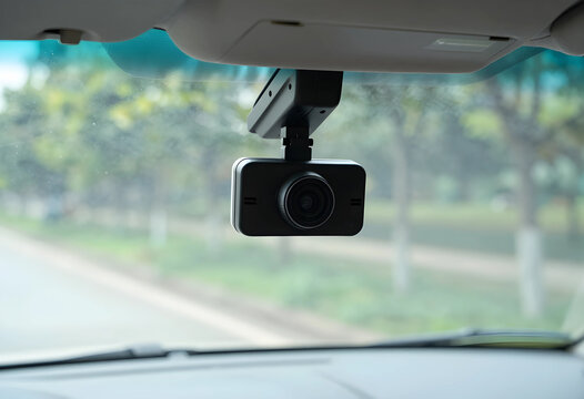 Dash cam mounted on a car windshield, recording road activity and providing vehicle security and evidence for accidents, the camera captures the view through the front glass