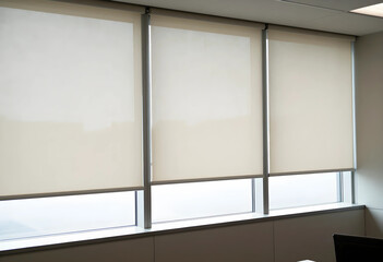 Fototapeta premium Modern office window with three beige roller blinds partially lowered, providing privacy and light control in a contemporary interior