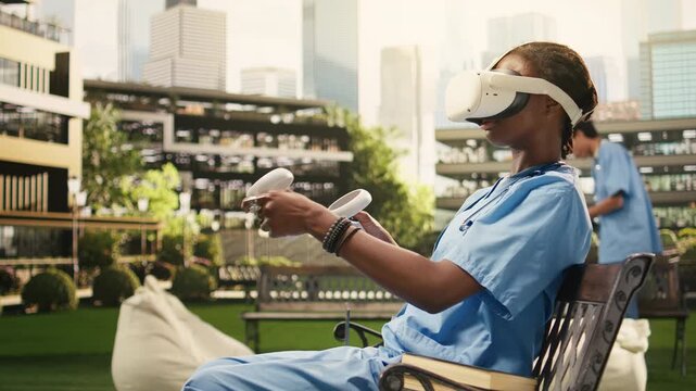 The medical student uses VR controllers and glasses in blue scrubs on a bench, using virtual reality technology for medical training on campus, during an immersive learning study session.