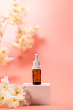 Serum dropper bottle with flowers on pink background