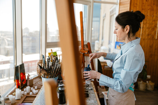 Female artist mixing paint in a colorful art studio