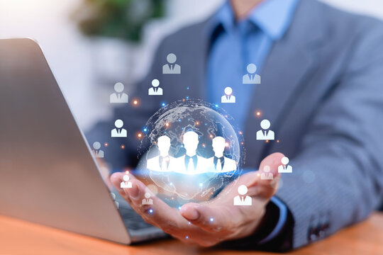Businessman using digital technology to connect a global workforce, with team icons around a glowing world globe, representing recruitment, networking, remote collaboration, and business growth.