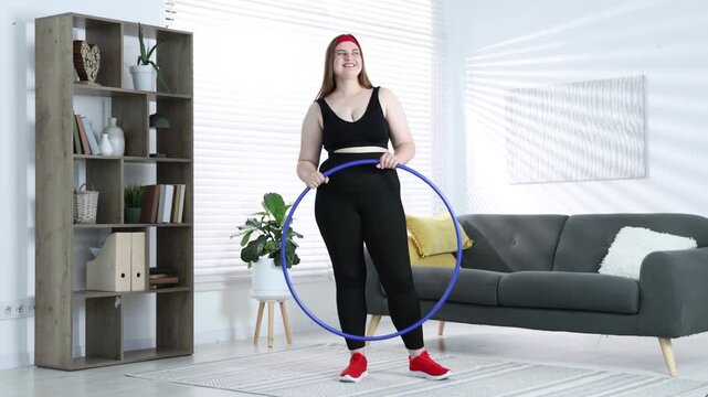 Overweight woman with hula hoop after training at home