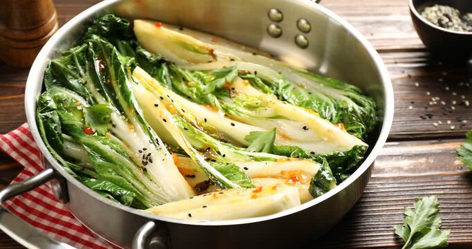 Tasty cooked bok choy cabbages with sesame seeds and sauce served on wooden table, closeup