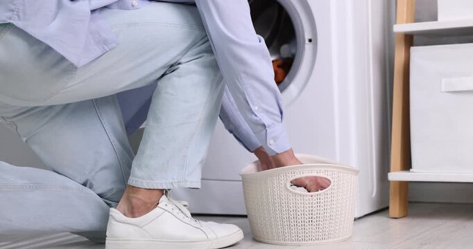 Man loading washing machine and setting cycle, closeup. Camera moving