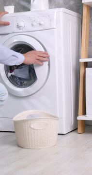 Man loading washing machine with laundry and setting cycle