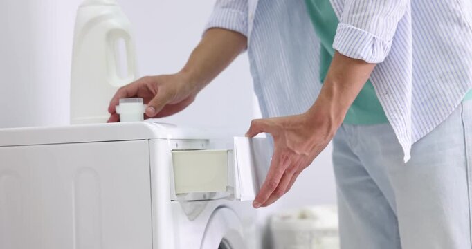 Man closing door of washing machine and adding laundry detergent, closeup. Camera moving