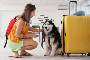 Young woman with a red backpack petting a husky dog next to a yellow suitcase, pet friendly travel concept, the scene suggests a journey or vacation with a beloved animal companion © Pixel-Shot