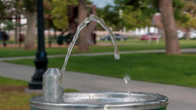 Park drinking fountain activates as a stream of fresh water begins flowing.