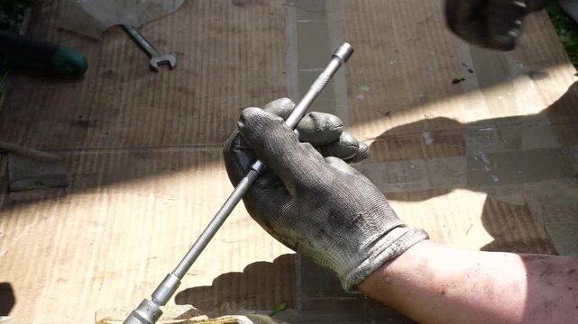 Mechanic wearing protective gloves assembling extension bar and ratchet wrench for car repair tools