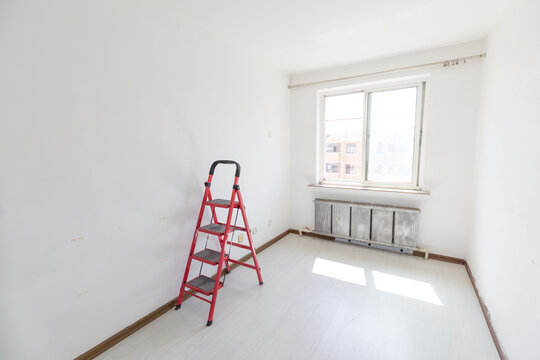 A red ladder in an empty room