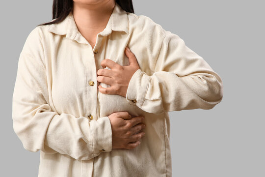 Young woman having heart attack on light background, closeup
