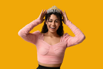 Happy young African-American woman in beautiful tiara on yellow background © Pixel-Shot