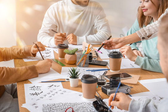 Group of students learning calligraphy and writing with brushes and ink during an art class or workshop