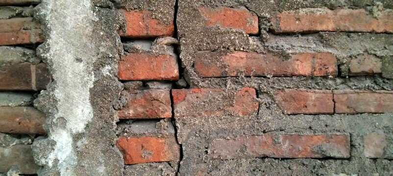Cracked cement plaster texture on an old red brick wall.