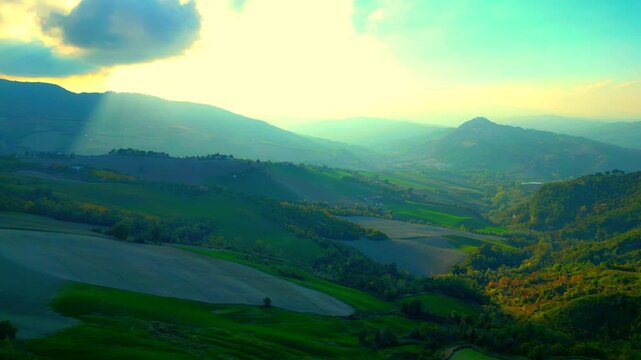 Wonderful aerial truck left pan right shot from near Santa Vittoria in Matenano, the Sibillini mountains in all their glory and warm, spiritual sunlight shining through from the peaks and the clouds