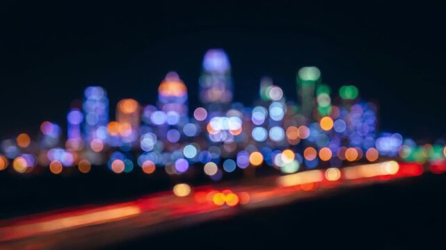 カラフルな円形ボケで描かれた都市の夜景シルエット。赤と黄の光がトラフィックのように流れる抽象的なループ映像。