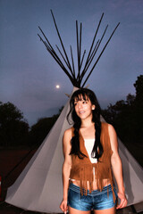 Young woman smiles near tipi at twilight © ExploringandLiving