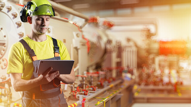 Industrial maintenance. Technician monitors industrial equipment with a tablet during machinery inspection, checking production systems, process performance and operational safety.