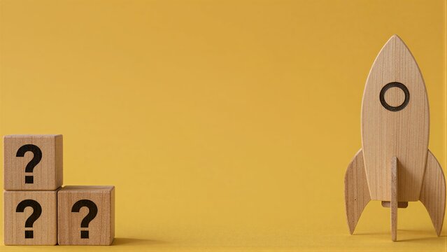 Wooden blocks with question marks stand beside a rocket, symbolizing uncertainty and launch.