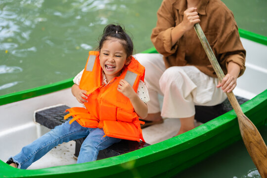 close-up of smiling preschool child girl in a life jacket aboard a rowboat.