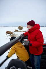 Grandfather and grandson feeding reindeer during a winter outdoor adventure © Drobot Dean