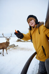 Young boy feeding reindeer during a winter outdoor adventure © Drobot Dean