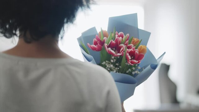Woman walks indoors holding fresh flower bouquet