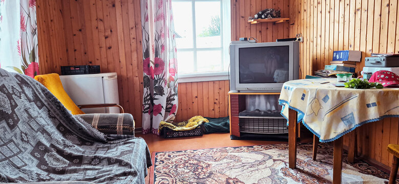 Cozy rustic house interior with wooden walls, vintage TV, round table and carpet
