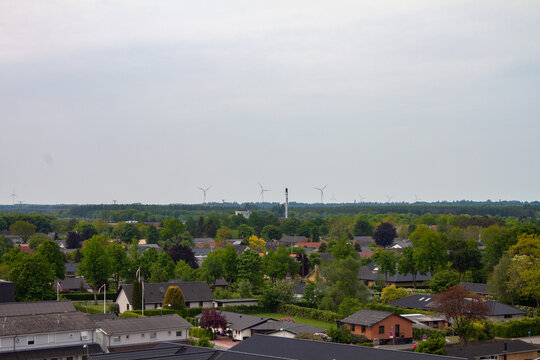 View of a small town in Denmark with homes and buildings in the foreground and wind turbines in the distance