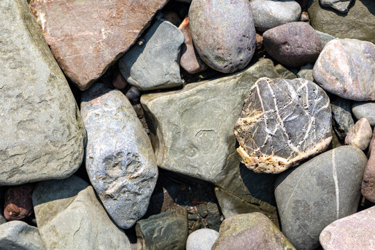 Quebec, Canada, 28 July 2026 : Close-up view of various smooth and rough rocks and pebbles on a natural surface