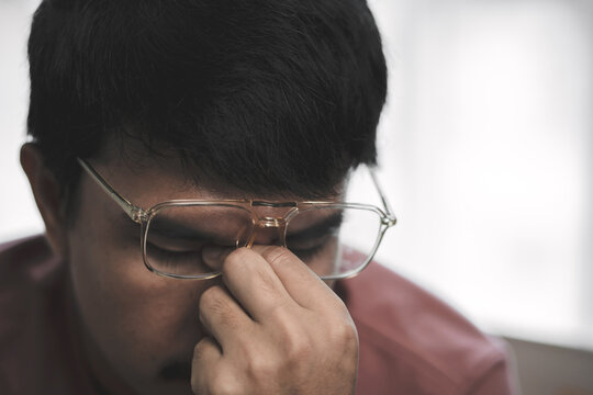 Asian Man Sitting Alone With Smartphone and Worried Expression, Representing Work Stress, Anxiety, Emotional Press. ure and Difficult Decisions in Modern Life . 