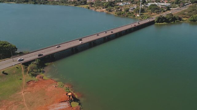 Honestino Guimaraes Bridge across Lake Paranoa, Brasilia, Federal District, Brazil, revealing moving traffic, freshwater reservoir and wooded shoreline, drone parallax.