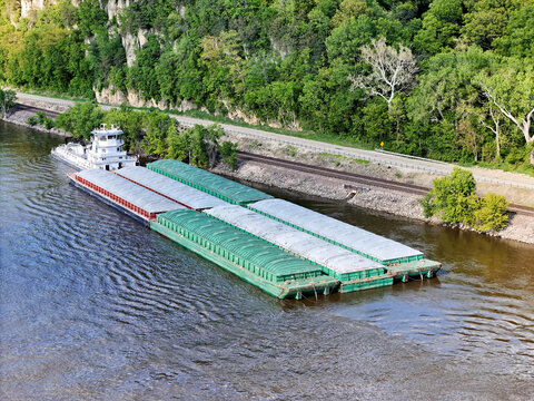 Aerial view of a tug boat with barges waiting outside the main channel next to the Mississippi shoreline.