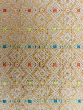 Golden songket woven fabric texture background with intricate geometric diamond pattern