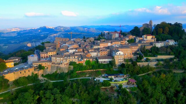 Impressive aerial pullback truck left pedestal up shot from Santa Vittoria in Matenano, the tightly-spaced town centre with its vintage buildings, churches, towers, perched on a verdant promontory